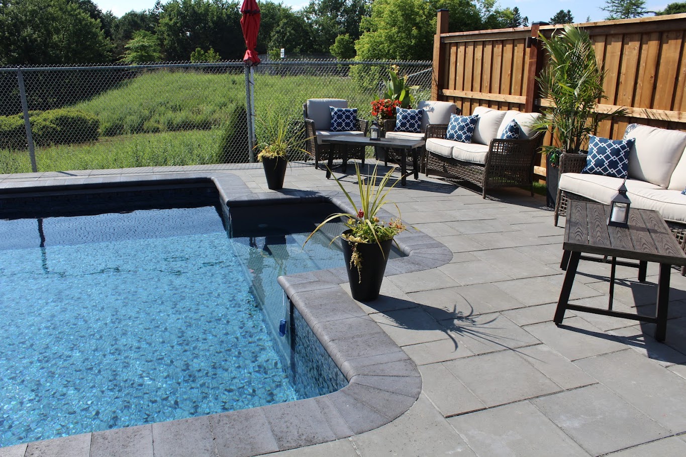 A vinyl in-ground pool with custom stonework around it and outdoor furniture.