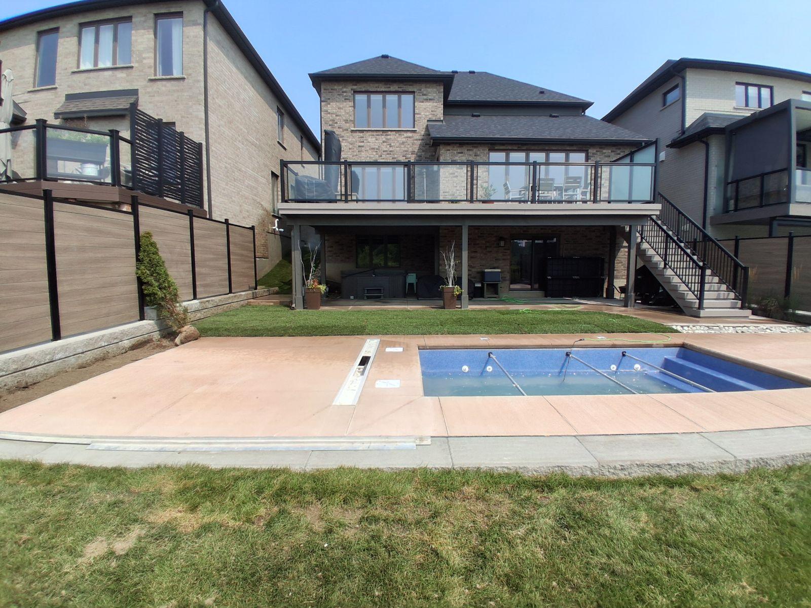 Backyard pool area with raised deck and privacy fencing