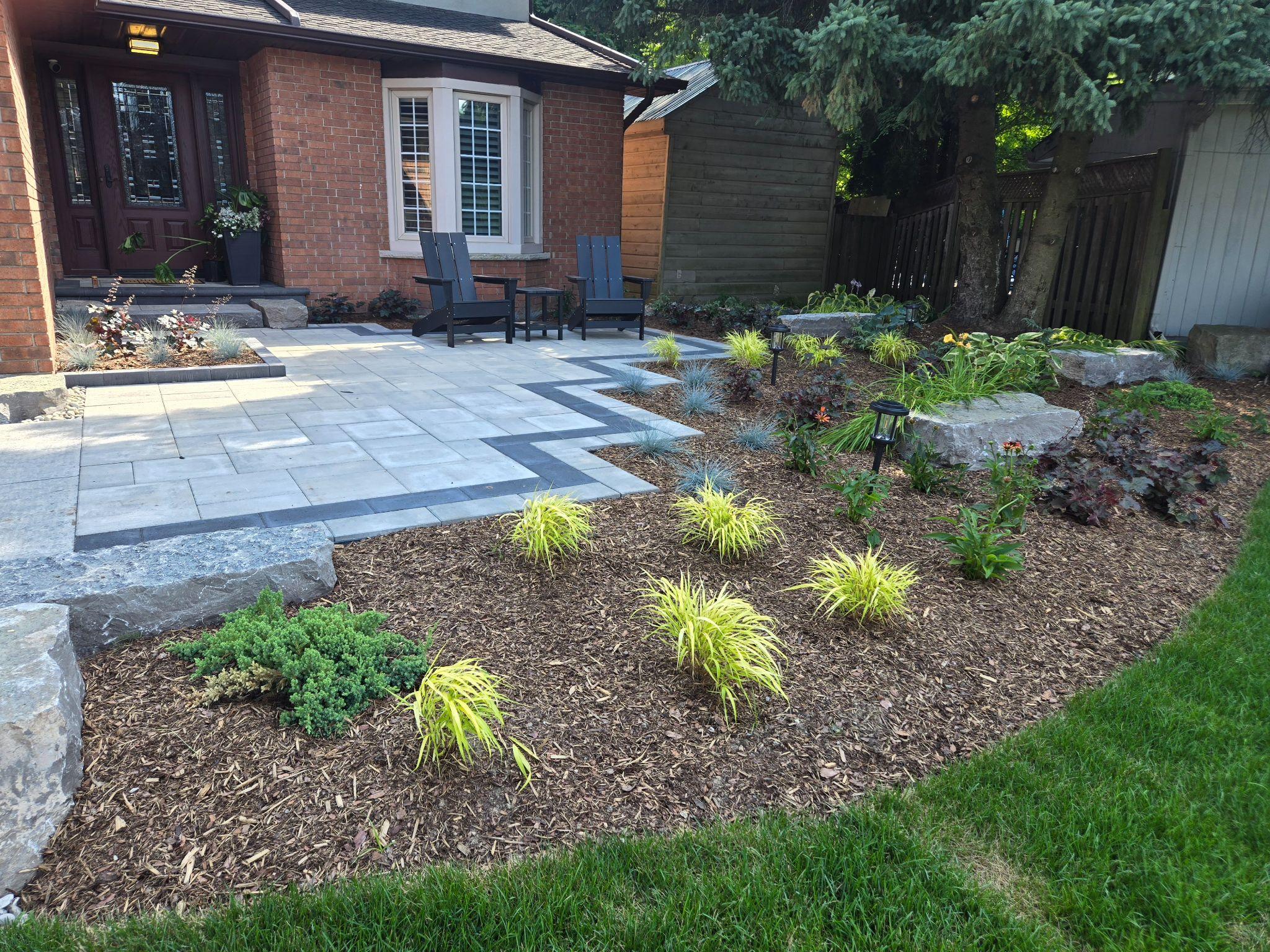 Front patio landscaping with pavers, mulch beds, and decorative stone