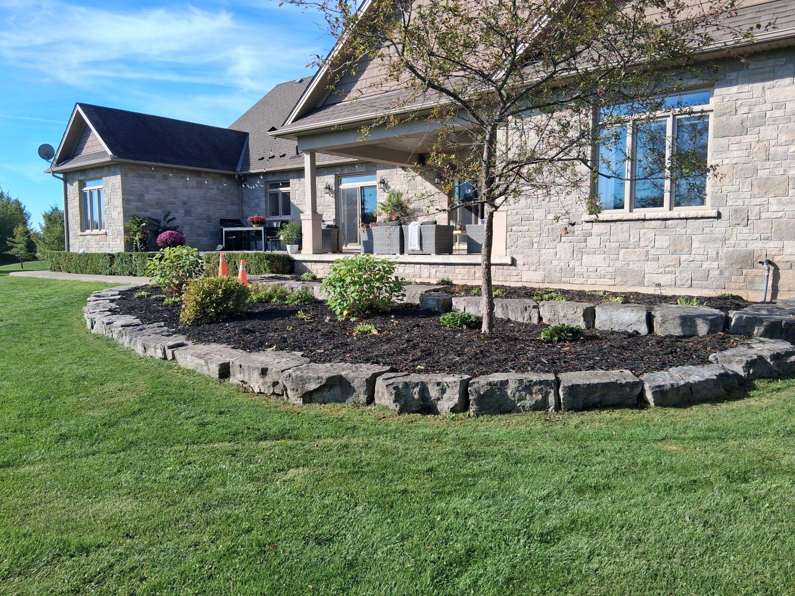 Stone-edged garden bed surrounding luxury backyard patio