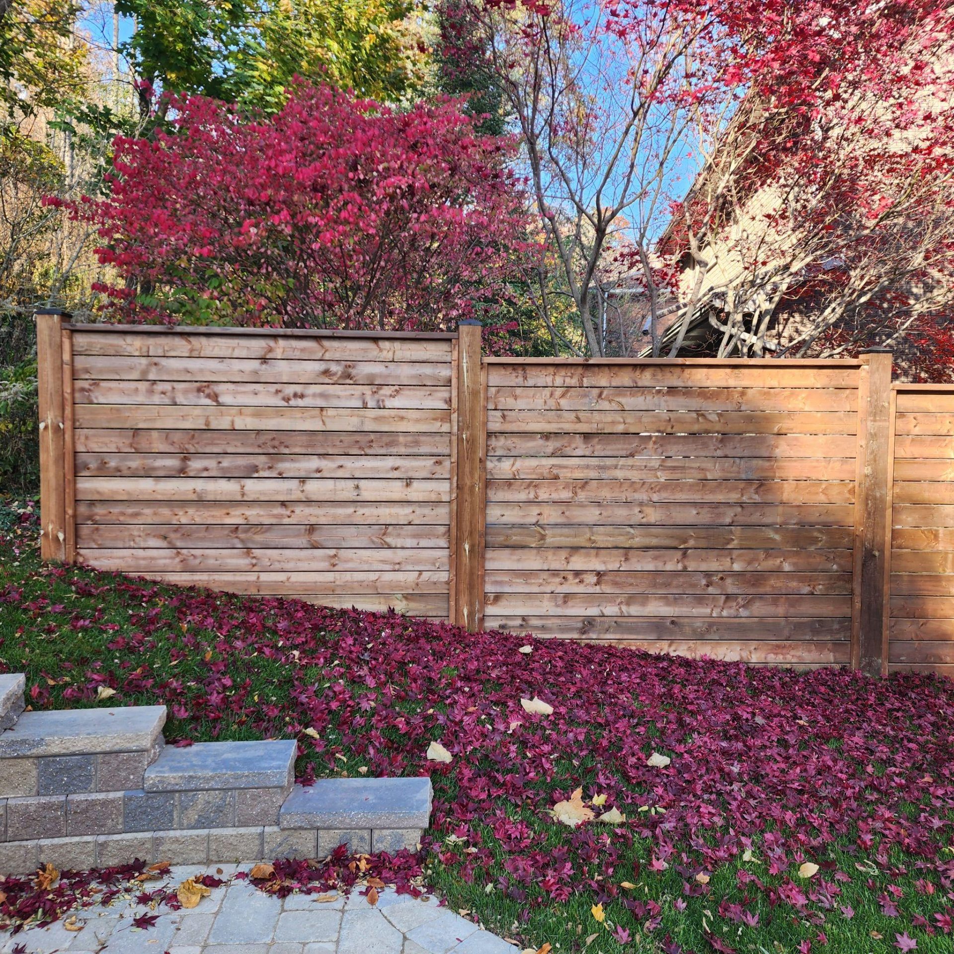 Wooden privacy fence with autumn foliage and retaining wall